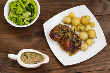 Pork medallions in mushroom sauce with new potatoes. Restaurant supply. Wooden table. Top view. Close-up