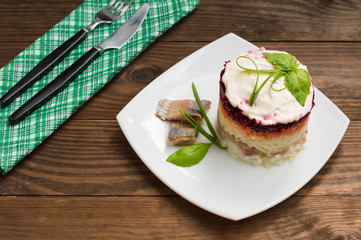 Shuba salad. Cooked beets, carrots, potatoes, onions, herring and mayonnaise. The classic Russian cuisine. Restaurant supply. Wooden table. Close-up. Top view