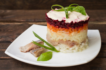 Shuba salad. Cooked beets, carrots, potatoes, onions, herring and mayonnaise. The classic Russian cuisine. Restaurant supply. Wooden table. Close-up. Top view