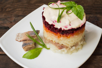 Shuba salad. Cooked beets, carrots, potatoes, onions, herring and mayonnaise. The classic Russian cuisine. Restaurant supply. Wooden table. Close-up. Top view