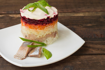Shuba salad. Cooked beets, carrots, potatoes, onions, herring and mayonnaise. The classic Russian cuisine. Restaurant supply. Wooden table. Close-up. Top view