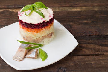 Shuba salad. Cooked beets, carrots, potatoes, onions, herring and mayonnaise. The classic Russian cuisine. Restaurant supply. Wooden table. Close-up. Top view