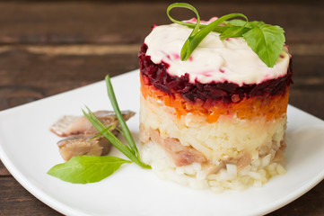 Shuba salad. Cooked beets, carrots, potatoes, onions, herring and mayonnaise. The classic Russian cuisine. Restaurant supply. Wooden table. Close-up. Top view