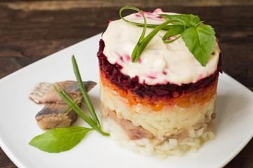 Shuba salad. Cooked beets, carrots, potatoes, onions, herring and mayonnaise. The classic Russian cuisine. Restaurant supply. Wooden table. Close-up. Top view