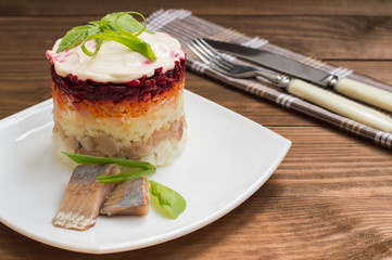 Shuba salad. Cooked beets, carrots, potatoes, onions, herring and mayonnaise. The classic Russian cuisine. Restaurant supply. Wooden table. Close-up. Top view