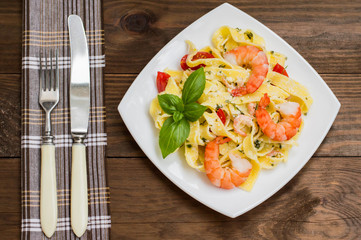 Fettuccine pasta in cream sauce with king prawns on a plate  the wooden table. Horizontal view from above. Top . Close-up