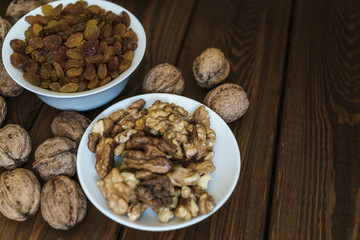 Raisins and walnuts in a bowl on a wooden background. Ingredients for cooking. H