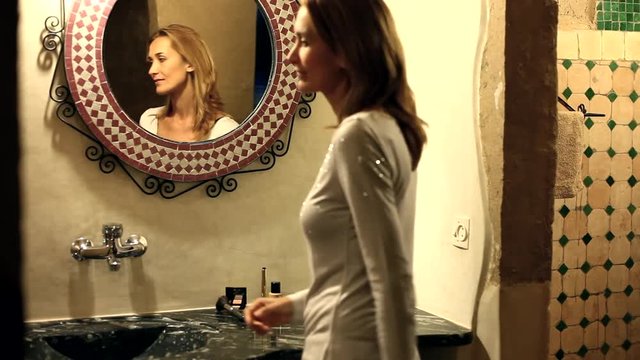 belle femme qui se maquille dans sa salle de bain