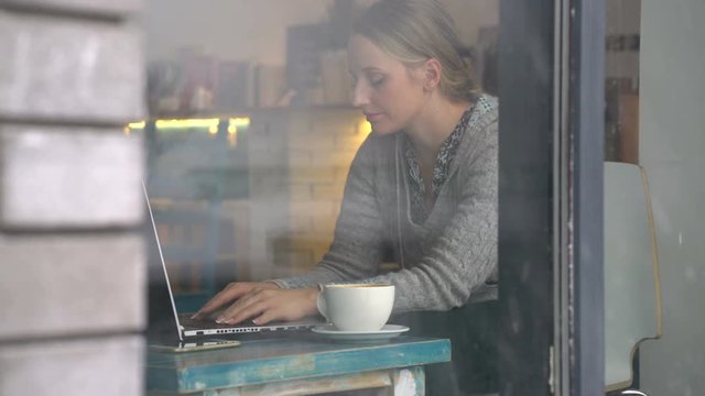 young woman working on a laptop in a cafe