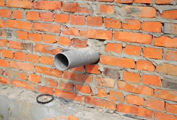 House brick wall over sewer pipe drainage system.