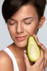 Skin Care And Beauty. Beautiful Woman Holding Avocado Near Face