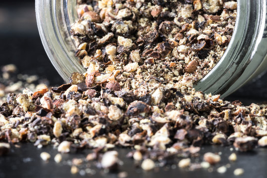 Coarsely ground black pepper spilling from a spice jar