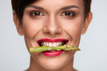 Healthy Eating.  Beautiful Woman Holding Asparagus Between Teeth
