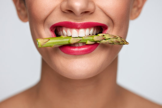 Healthy Diet. Beautiful Woman Mouth Holding Fresh Asparagus