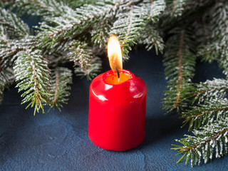 Fototapeta na wymiar Dark christmas background with red candle and fir tree branches