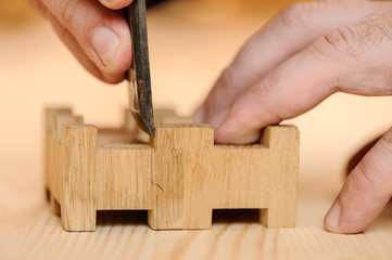 Carpenter hands cutting wood with chisel