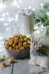 Caramel popcorn on a winter background with Christmas tree