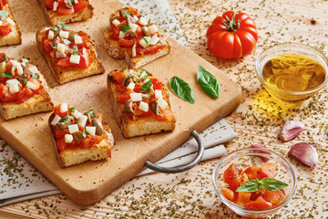 Bruschetta tomato, cheese, olives and garlic on cutting board and wooden table
