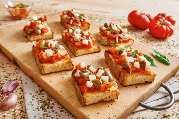 Bruschetta tomato, cheese, olives and garlic on cutting board and wooden table