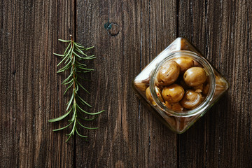 Olives in the jar and rosemary on wooden table