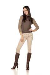 young woman in trousers and high boots posing on white background