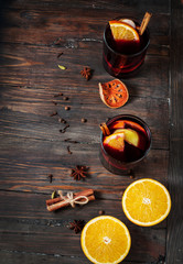 Hot mulled wine with spices, apple and orange on wood