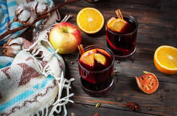 Hot mulled wine with spices, apple and orange on wood