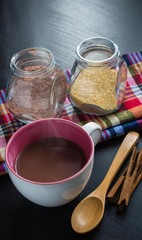 Hot chocolate cup with cinnamon sticks, wooden spoon and sugar j