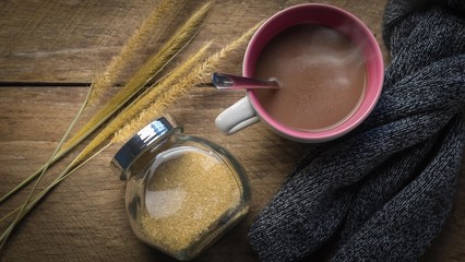 Hot chocolate cup, sugar jar and scarf on wooden table