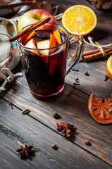 Hot mulled wine with spices, apple and orange on wood