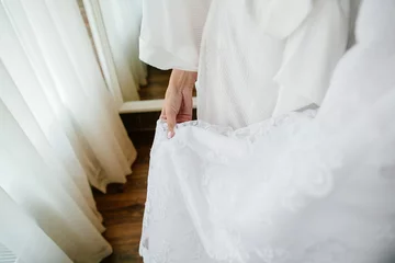 Foto op Plexiglas Wedding dress. Bride's hand holding wedding dress. Detail of lacy wedding dress. Closeup. © Maksym Azovtsev