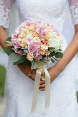 Wedding bouquet of flowers. Bride holds beautiful wedding bouquet of flowers in hands. Closeup.