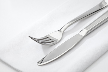 close up view of nice steel fork and knife on white napkin