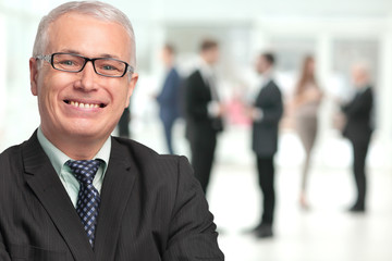 Happy mature business man looking at camera with satisfaction at office