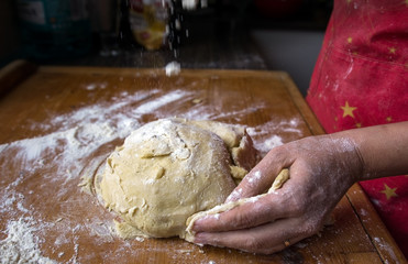 Female hands knead the dough for the cake and sprinkle flour