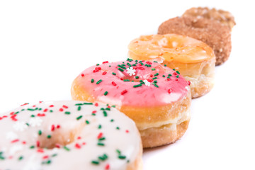 Frosted donut lineup shallow depth of field isolated on a white background