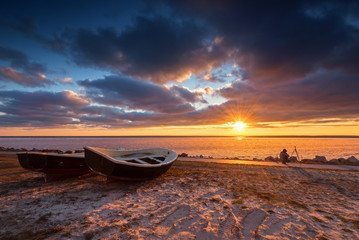 Fishing boats on the shore and frozen Baltic sea at sunset time. Poland, Europe.