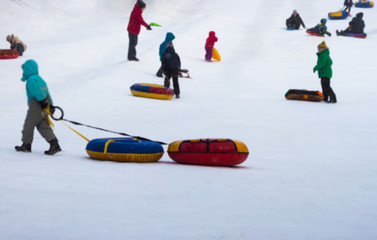 Naklejka premium Boy pulls snow tubings in one of snowy park, winter leisure, active lifestyles, childhood, Christmas. Selective focus. With place for your text