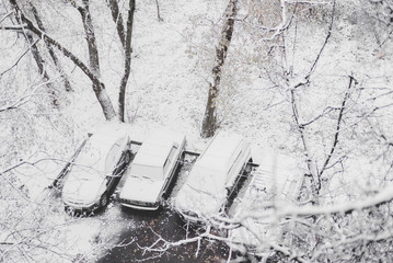Автомобили в снегу на парковке, покрытые снегом...