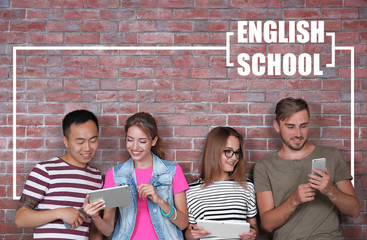 Young people using modern devices for studying. Text ENGLISH SCHOOL on brick wall background