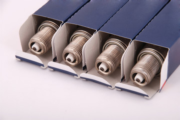 Four new spark plugs in paper packaging