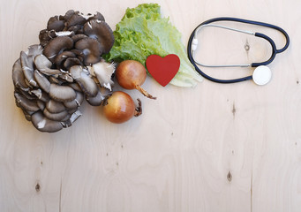 Health care heart green onions mushroom oyster mushrooms lettuce leaf stethoscope concept. Healthy food in heart and cholesterol diet vision on on white isolated wooden board background