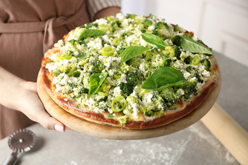 Woman holding vegetarian pizza with cheese and vegetables