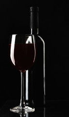 Glass of wine and a bottle on black background