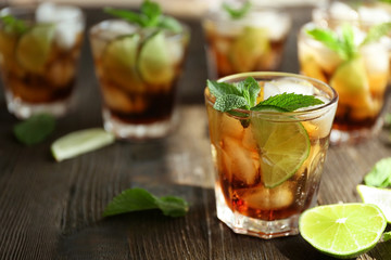 Glasses of cocktail with ice and mint on wooden table closeup
