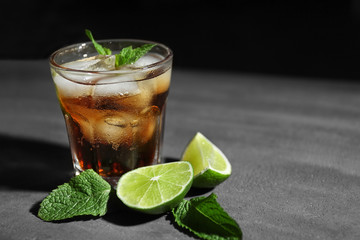 Glass of cocktail with ice, lime and mint on dark textured background