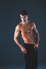 Fototapeta premium Strong athletic man standing on black background