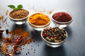 Aromatic spices in glass bowls on grey background