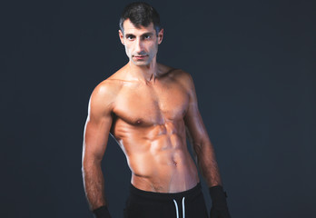 Fototapeta na wymiar Strong athletic man standing on black background