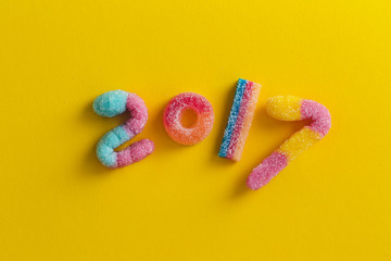 Happy New Year 2017. Numbers made of brightly colored candies on yellow background.